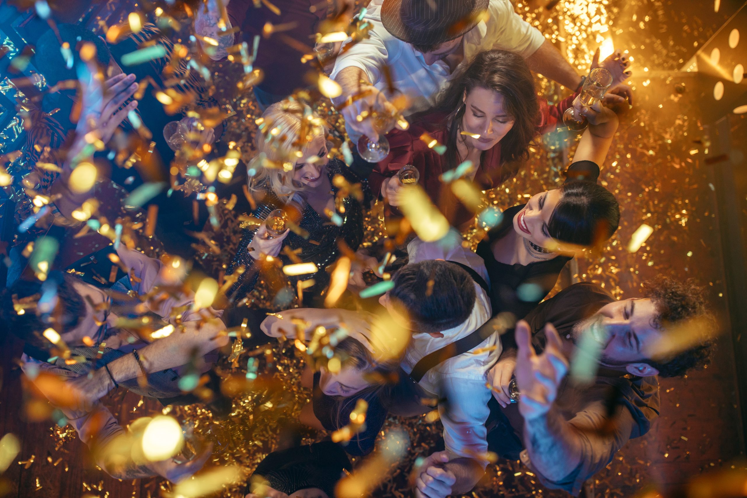Group of friends partying in a club and moving to the music surrounded by confetti
